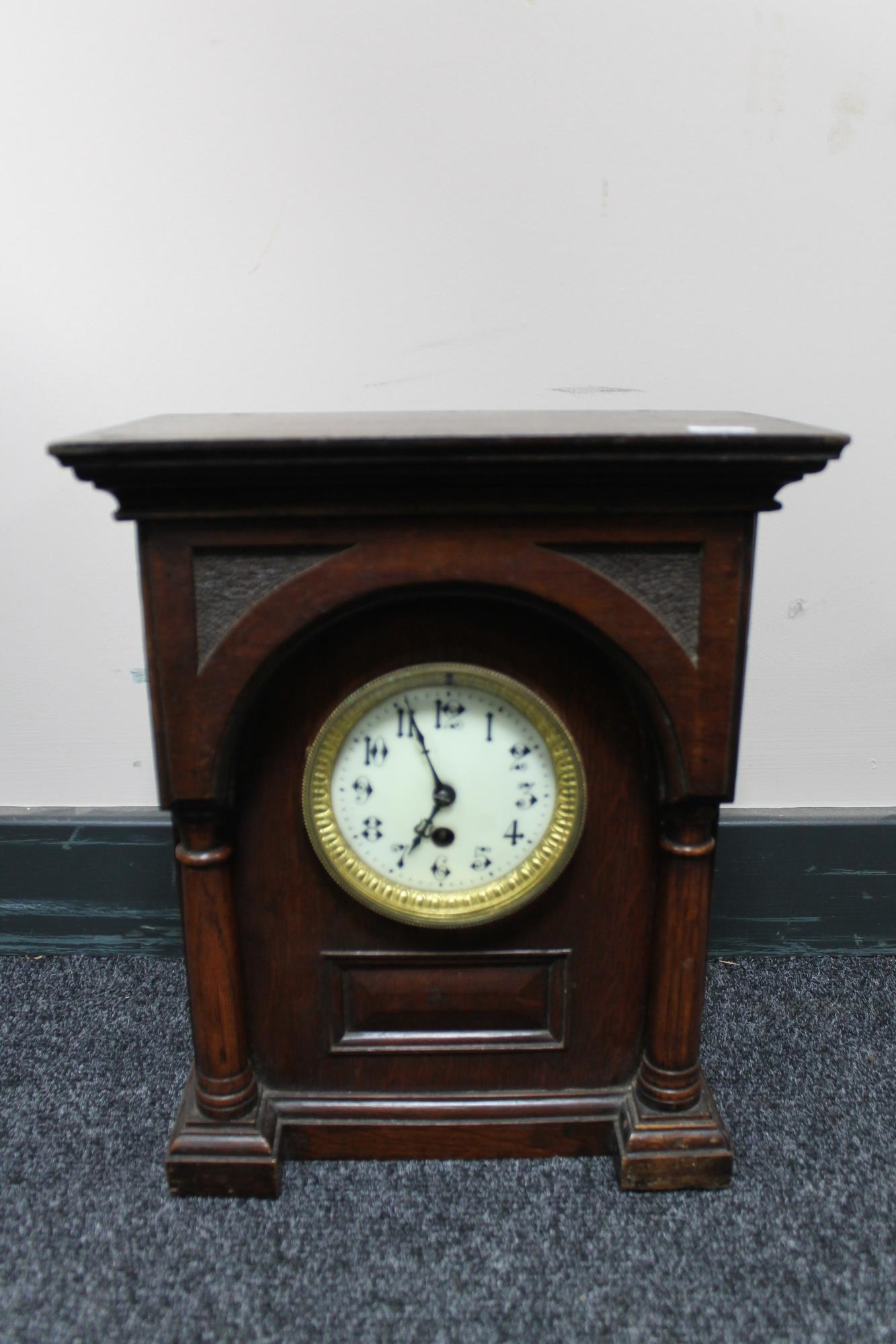 An antique oak cased continental bracket clock with brass and enamelled dial