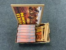 A box of six Zulu Dawn VHS box sets and a further five framed Zulu prints