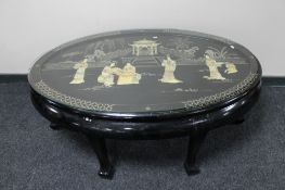 A large oval black lacquered Japanese coffee table with geisha mother of pearl decoration