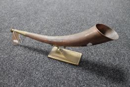 An antique brass and copper horn on brass stand