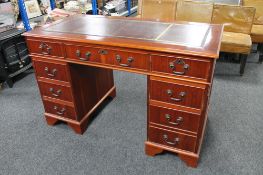 A mahogany twin pedestal writing desk with maroon tooled leather inset top