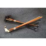 Eight assorted walking sticks together with a brass walking stick head
