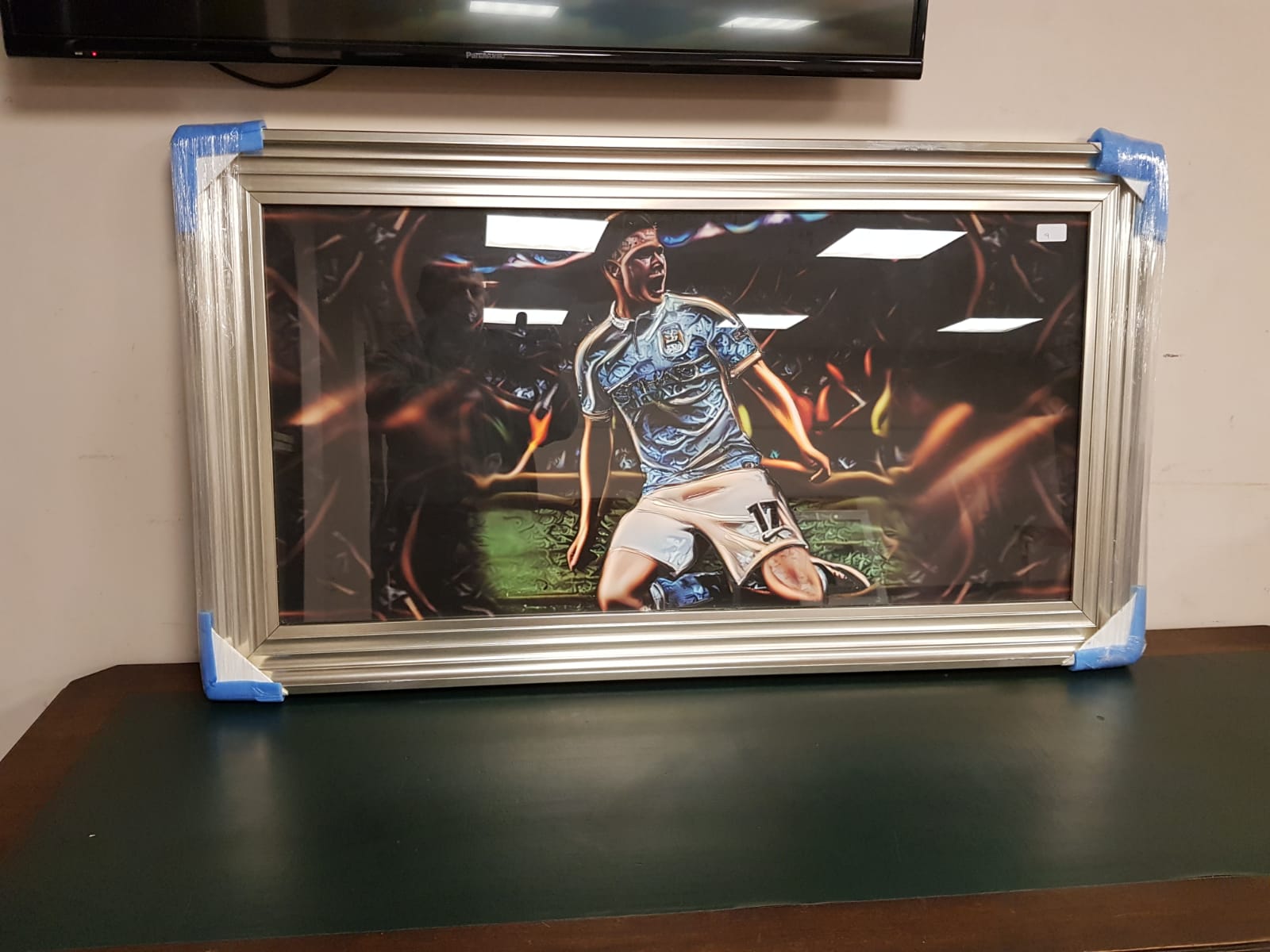 A framed print of a footballer in blue,
