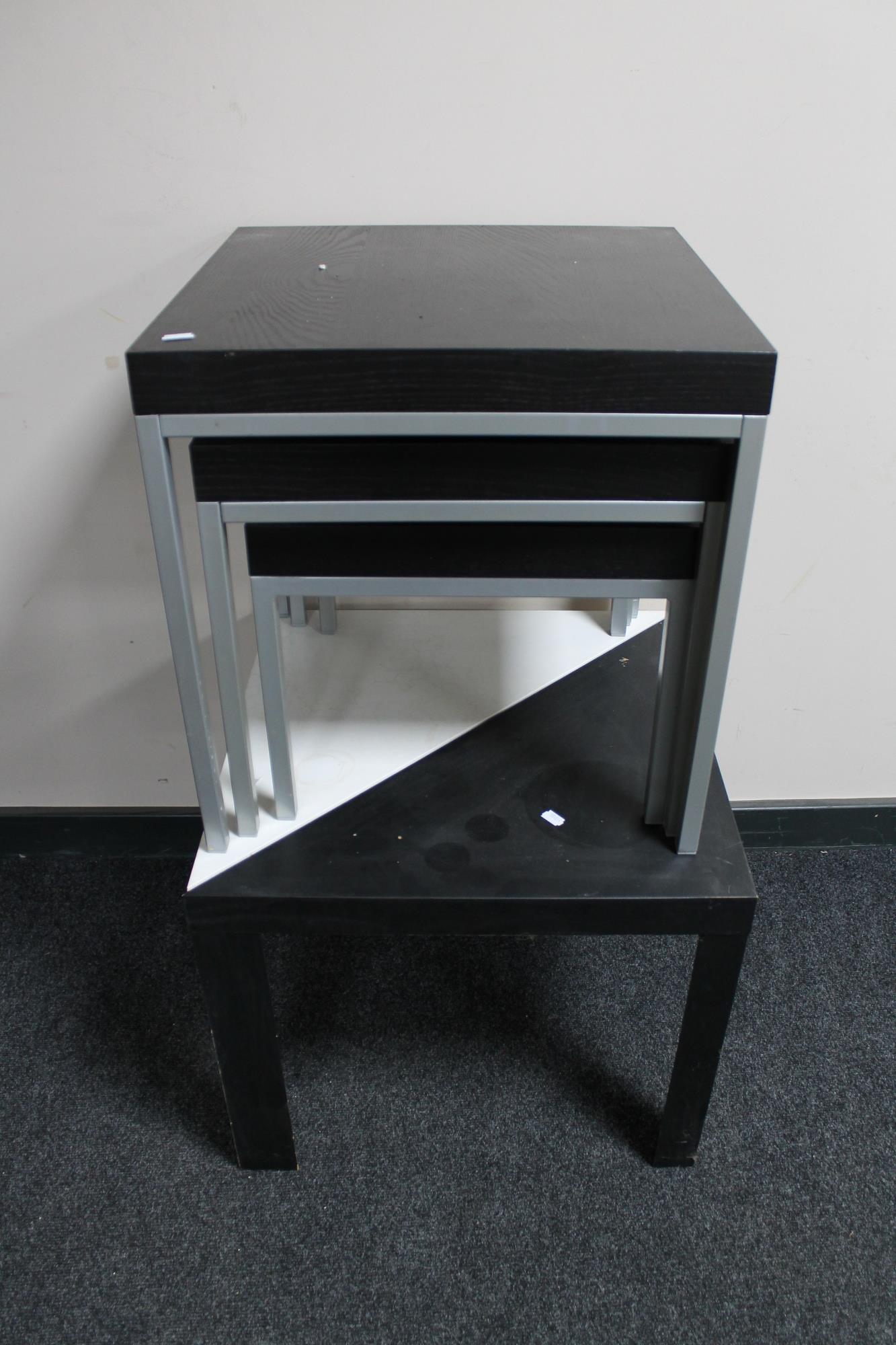 A nest of three black ash tables on metal legs,