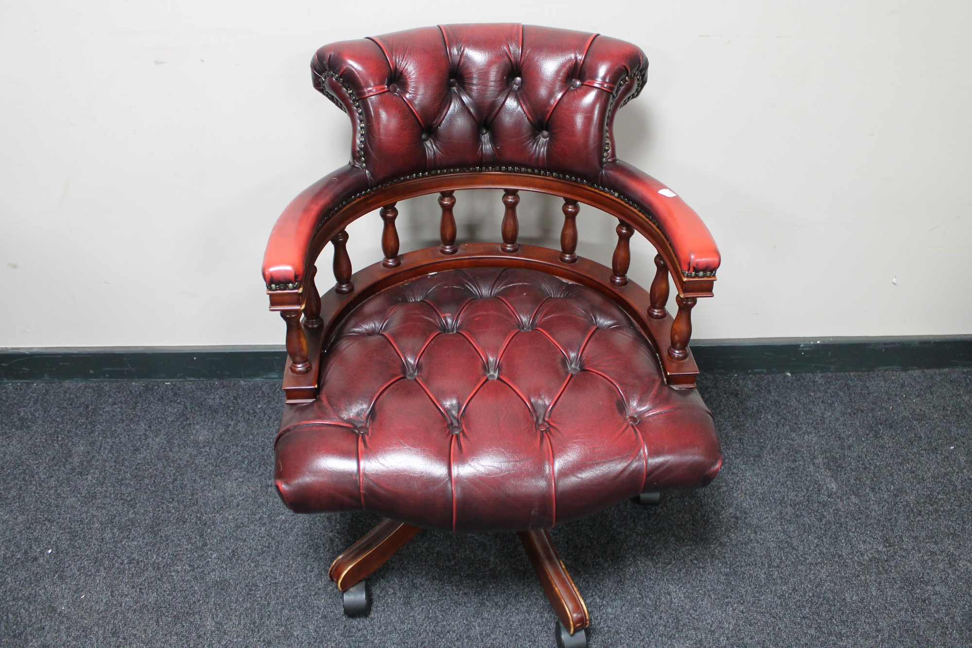 A red button leather swivel captain's armchair