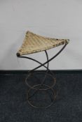 A wrought iron wicker seated stool