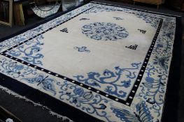 A large fringed woollen Chinese carpet on cream ground with blue borders