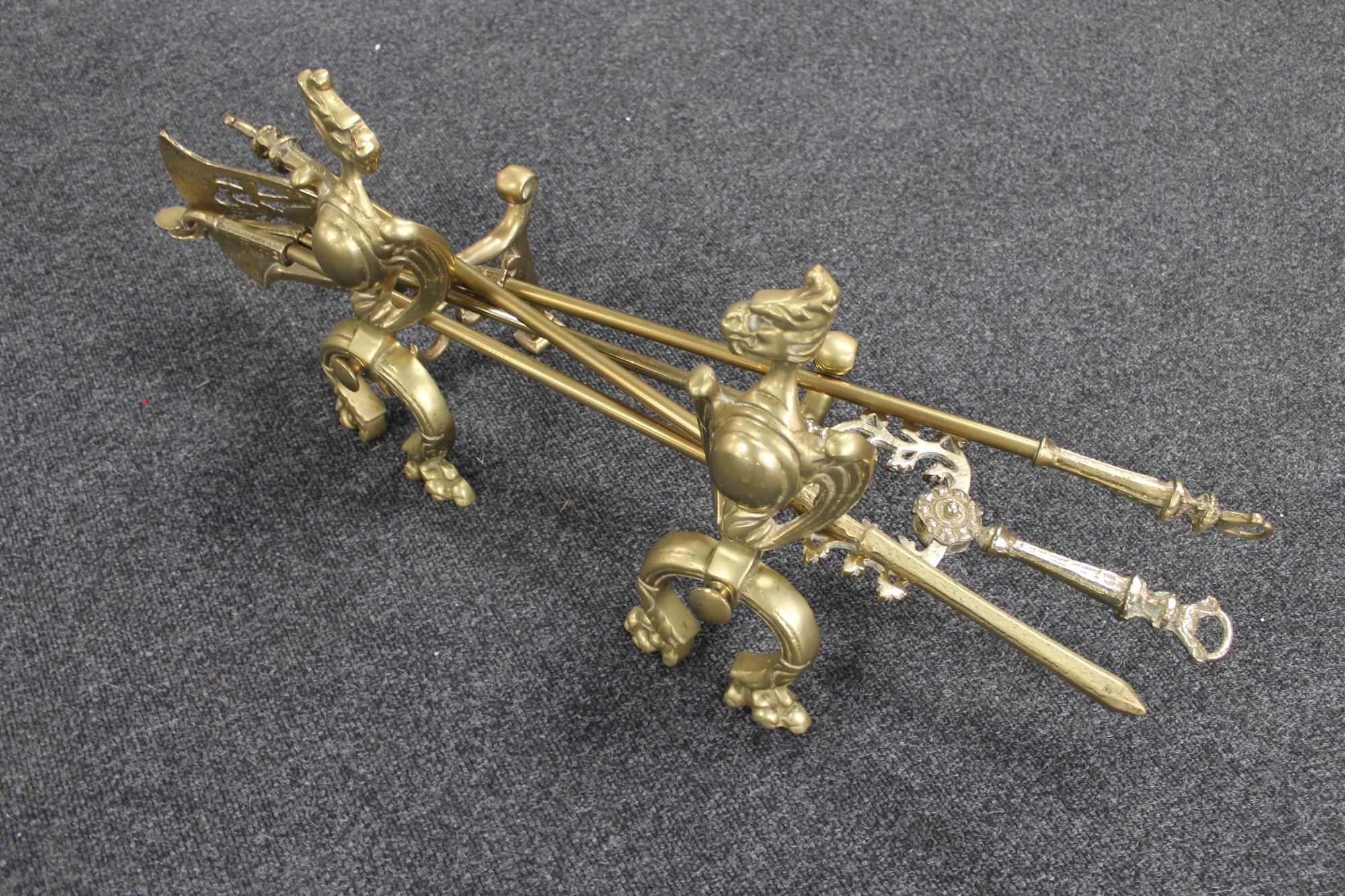 A pair of Victorian brass fire dogs ion the form of griffins together with a three piece Victorian