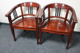 A pair of hardwood armchairs in a mahogany finish