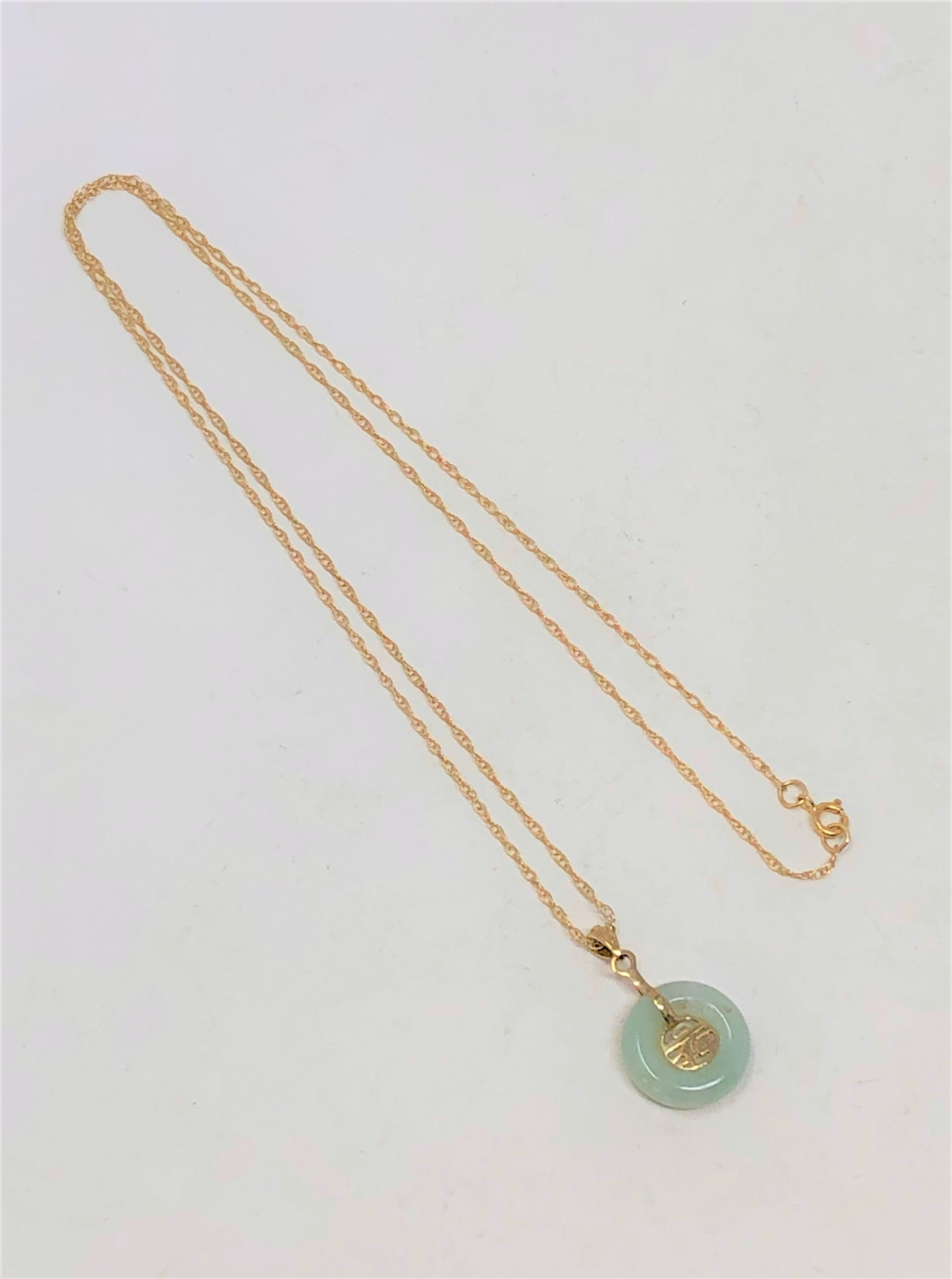 A jade disc pendant on 9ct gold chain CONDITION REPORT: 1.