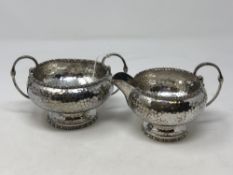 A hammered-silver cream jug and matching sugar basin,