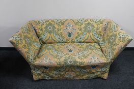 An early 20th century settee on oak legs with loose cover