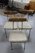 Three mid 20th century teak backed and metal framed dining chairs upholstered in cream vinyl