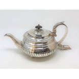 A Georgian silver teapot, maker ET, city and date marks rubbed, of gadrooned form on four ball feet,