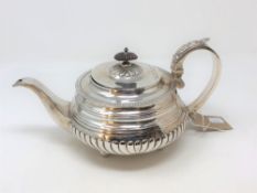 A Georgian silver teapot, maker ET, city and date marks rubbed, of gadrooned form on four ball feet,