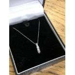 A 10ct white gold three stone diamond pendant on chain