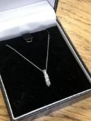 A 10ct white gold three stone diamond pendant on chain