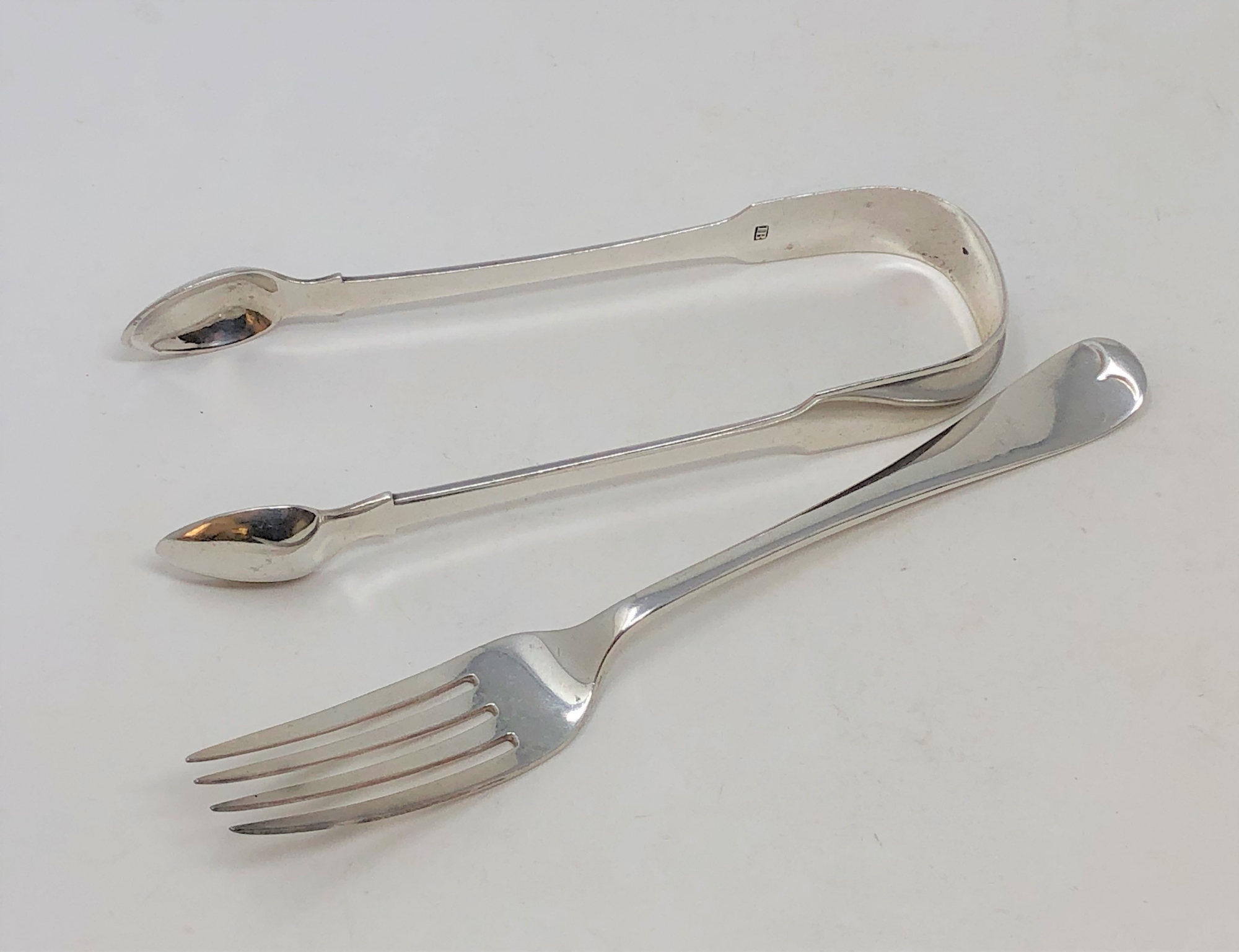 A pair of Georgian silver sugar tongs and a silver dessert fork, 73.6g gross.