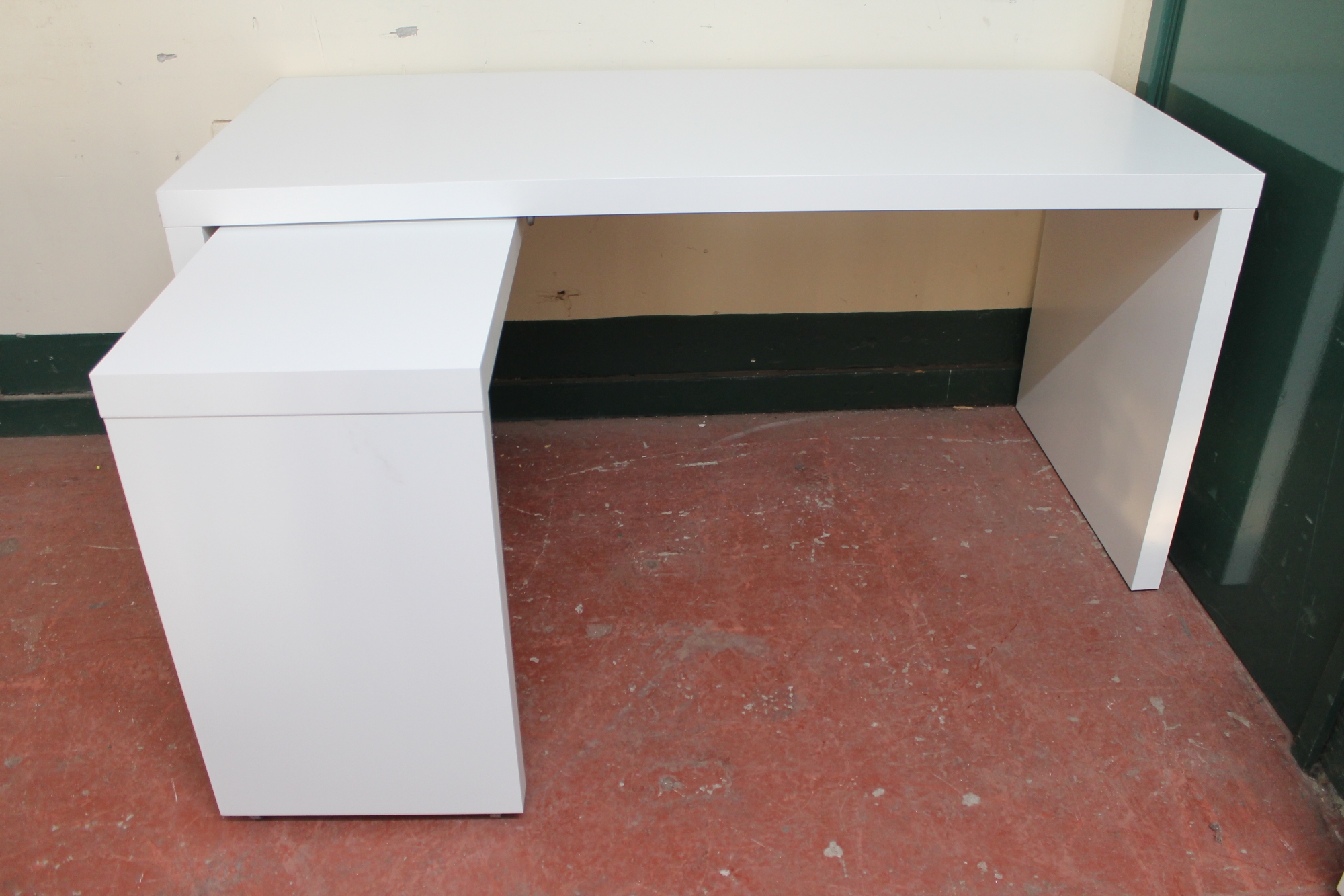 A white office L-shaped desk with three drawer metal under-desk filing chest