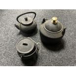 Two miniature cast iron cooking pots with lids together with a cast iron kettle with lid