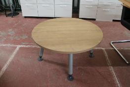 A circular oak effect office table with adjustable legs