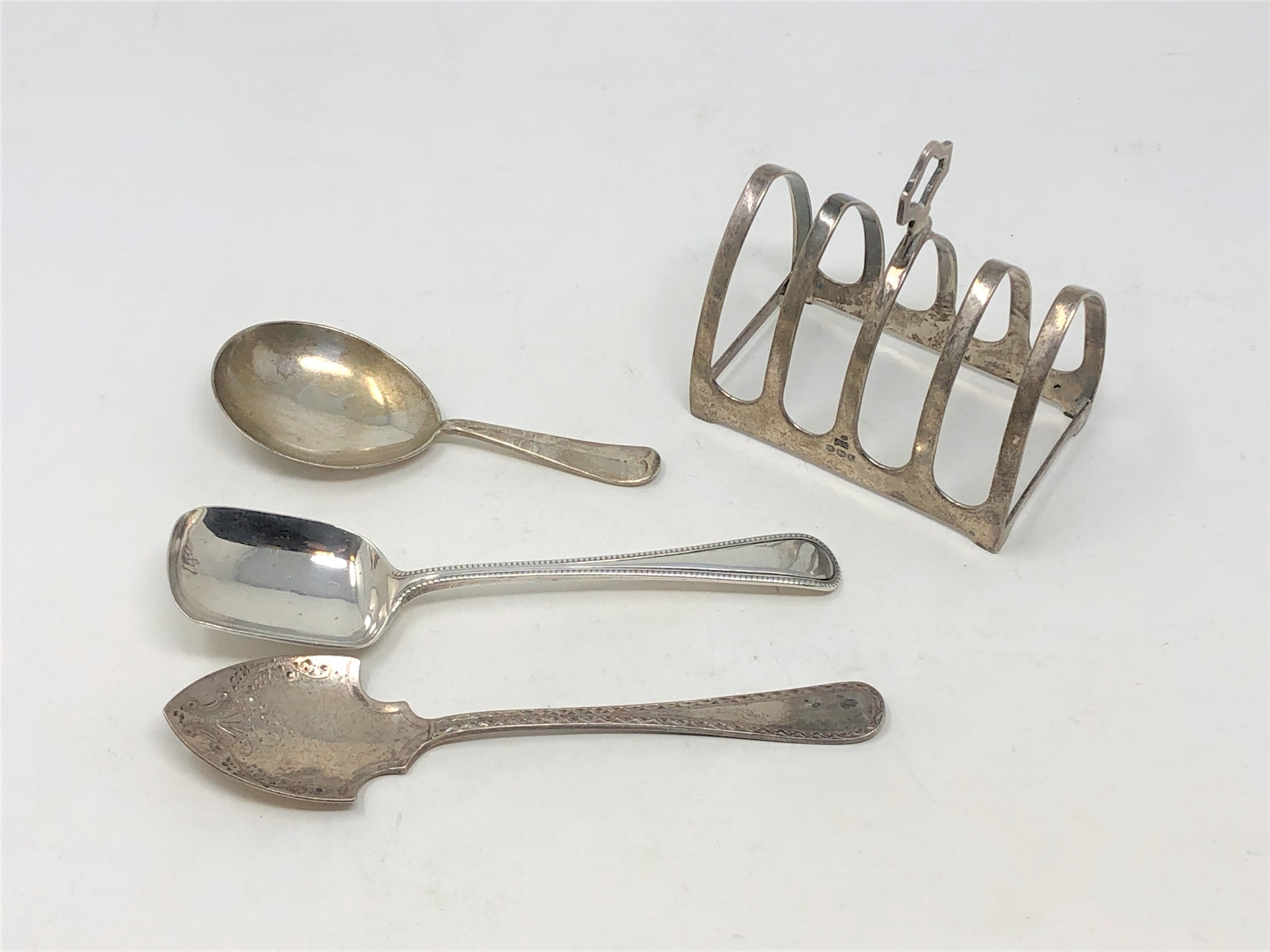 A silver five bar toast rack and three spoons.