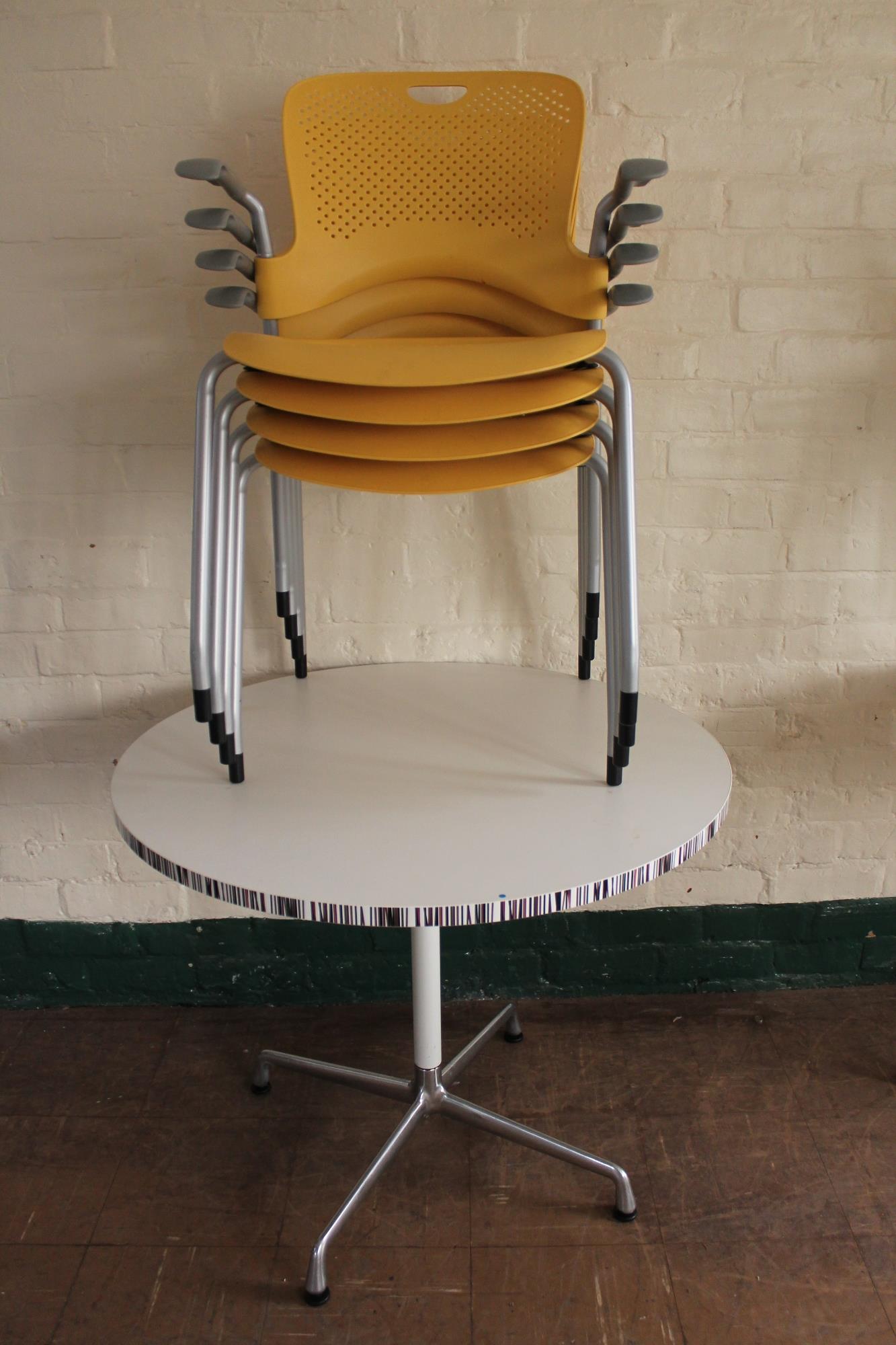 A circular pedestal cafe table and four plastic armchairs