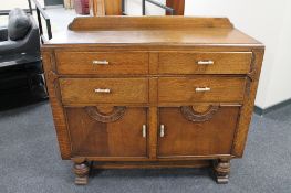 A 1930's oak double door sideboard fitted with four drawers
