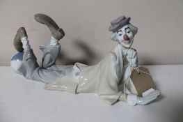 A Lladro figure of a clown lying with foot on ball