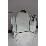 A frameless bevelled mirror on white painted stand