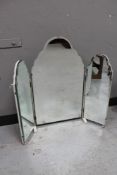 A frameless bevelled mirror on white painted stand