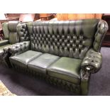 A green buttoned leather three seater wing backed settee