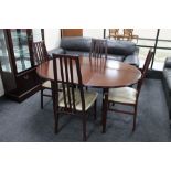 A contemporary circular mahogany extending dining table with leaf together with four rail backed