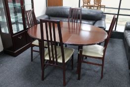 A contemporary circular mahogany extending dining table with leaf together with four rail backed