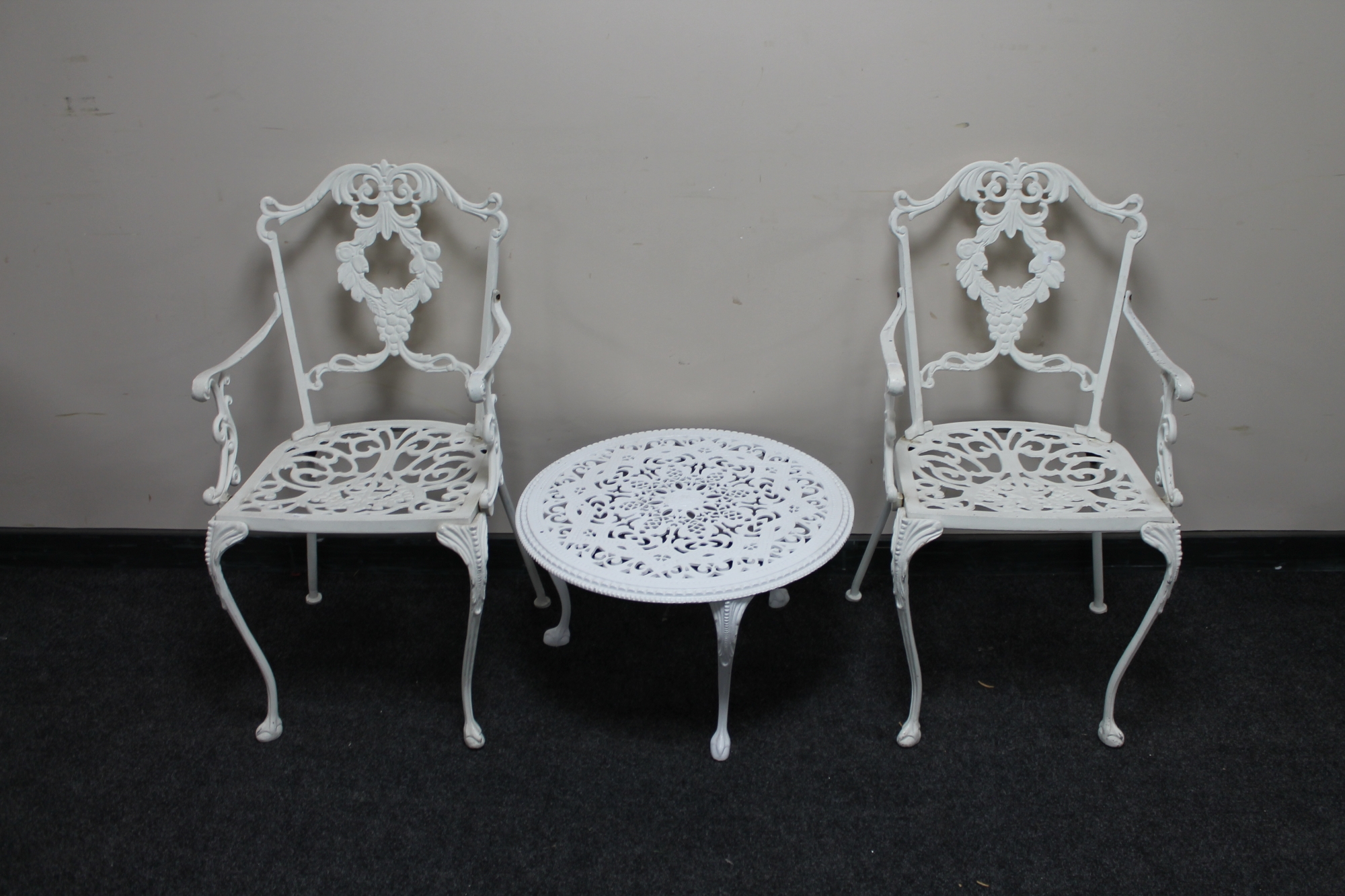 A pair of wrought metal painted patio chairs and circular coffee table