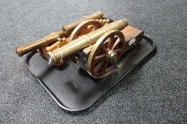 A tray of three brass and copper cannons on wooden stands