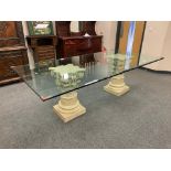 A contemporary glass topped twin pedestal dining table on Corinthian style columns,