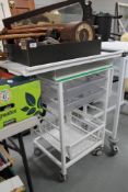 A metal medical trolley with adjustable top fitted two plastic trays and wire mesh tray