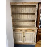 An antique pine kitchen dresser with double door cupboards and drawers beneath