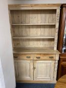 An antique pine kitchen dresser with double door cupboards and drawers beneath