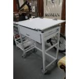 A metal medical trolley with adjustable top fitted a drawer