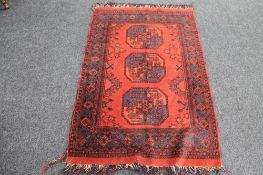 A fringed Afghan Bokhara rug on red ground