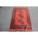 A fringed Afghan Bokhara rug on red ground