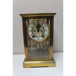 A brass and glass cased anniversary clock with brass and enamelled dial,