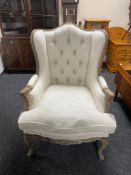 A wingback armchair in beige button fabric