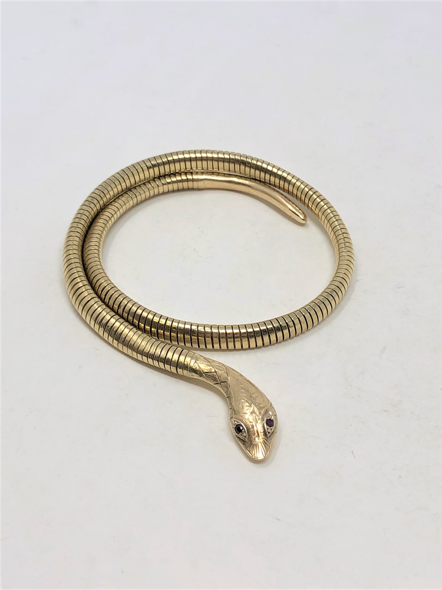 A 9ct gold and steel spring snake bracelet set with red eyes 29.6g gross.