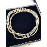 An antique triple strand pearl necklace with diamond set clasp