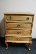 A blonde oak four drawer chest