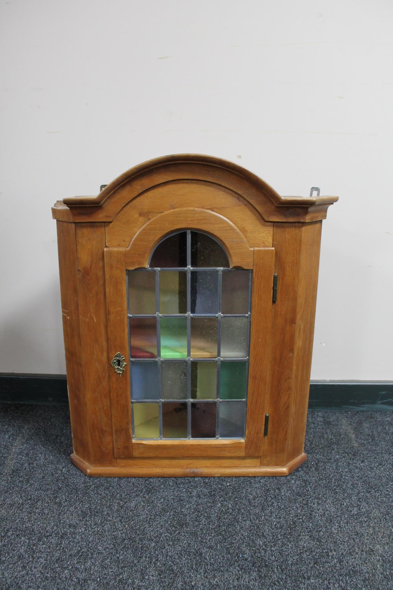 A blonde oak hanging corner cabinet