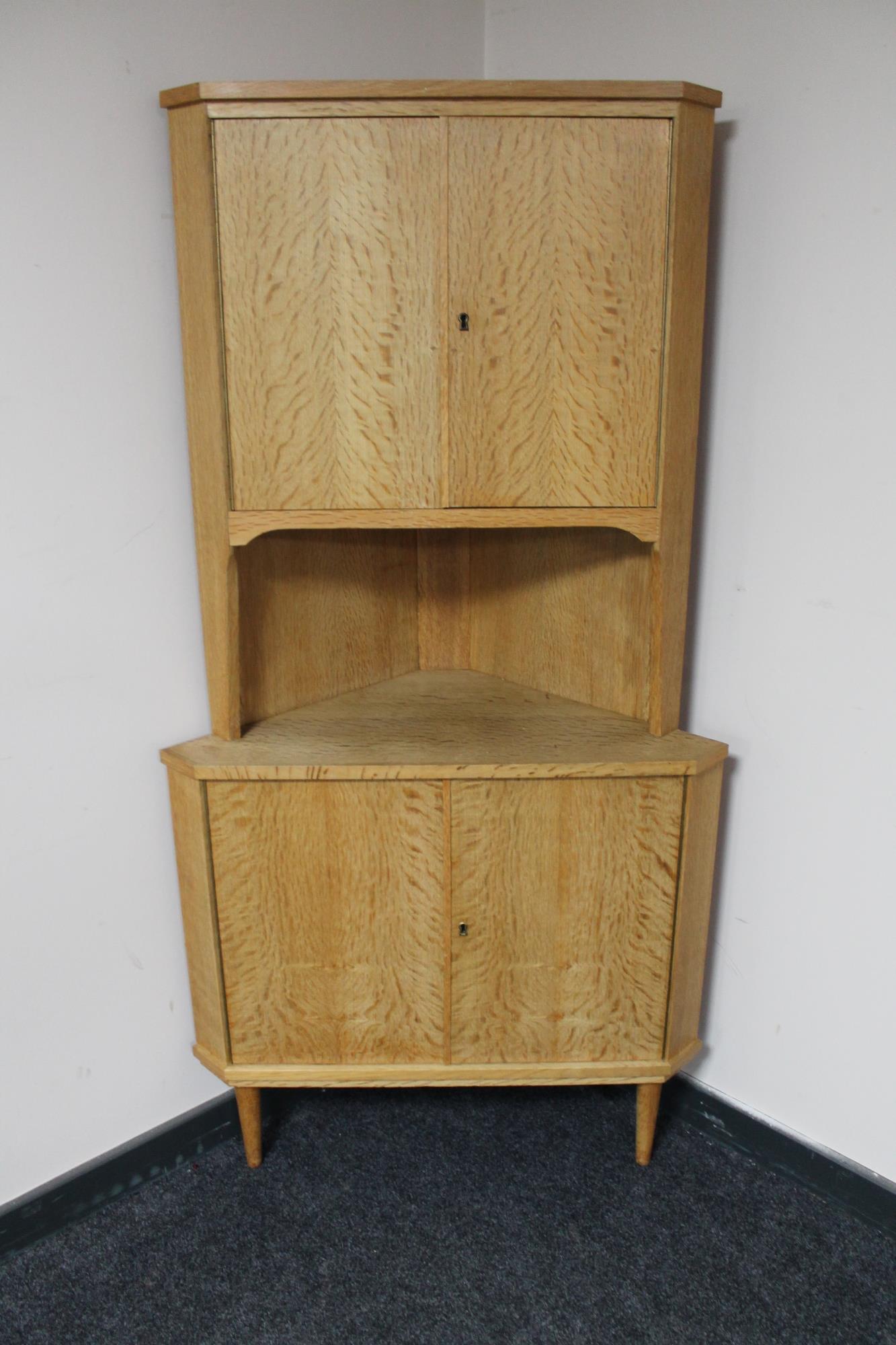 A blonde oak double door corner cabinet